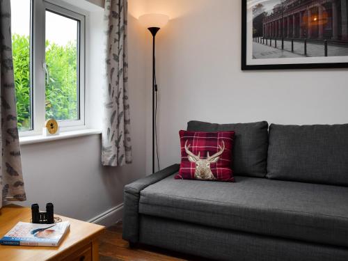 a living room with a gray couch with a red pillow at The Old Stables in Leamington Spa