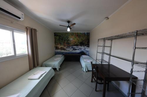 a room with two beds and a table and a painting at Hotel Pousada Do Leão in Lençóis Paulista