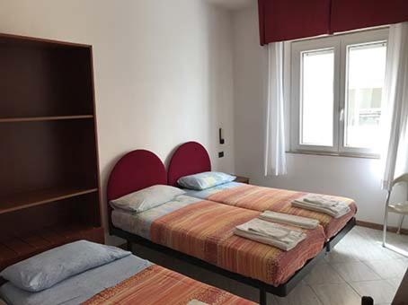 1 dormitorio con 2 camas y ventana en Hotel L&V, en Rímini