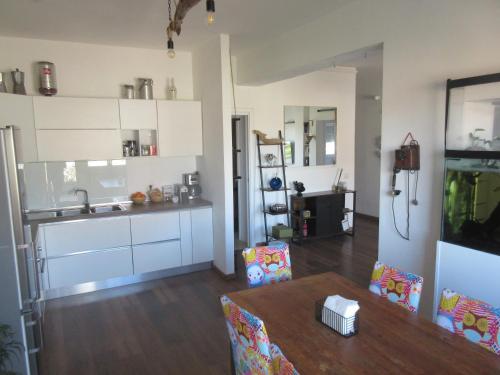 a kitchen with white cabinets and a wooden table at Rooftop Appia antica, Attico silenzioso residenziale in Rome