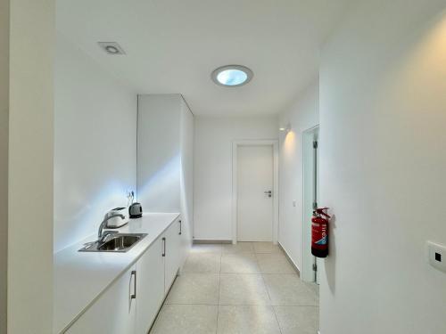 een witte keuken met een wastafel en een spiegel bij Feelgood Homestay Sagres in Sagres