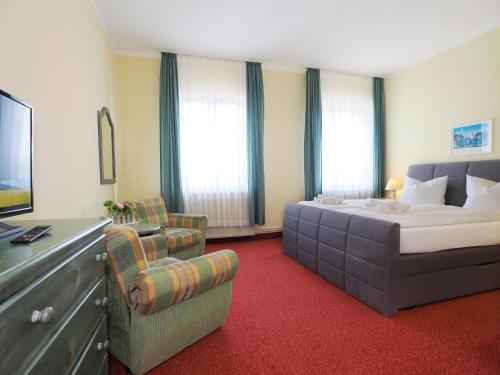 a bedroom with a bed and a couch and a chair at Hotel See-Eck in Heringsdorf
