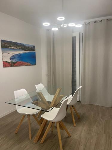 a dining room with a glass table and white chairs at Residenza Tramontana in Elmas