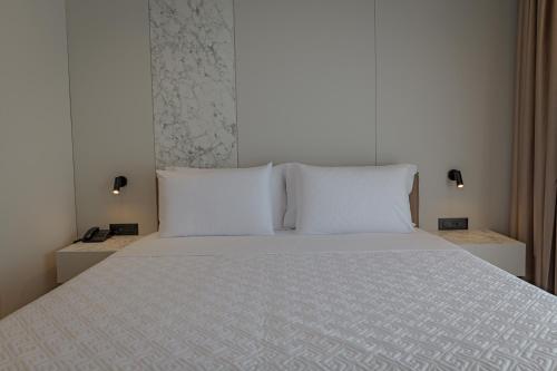 a bedroom with a bed with white sheets and pillows at Hotel Teuta in Sarandë