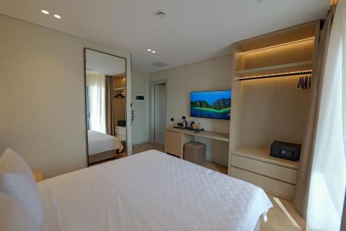 a bedroom with a white bed and a mirror at Hotel Teuta in Sarandë