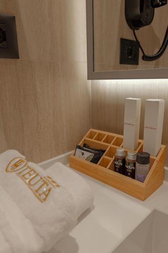 a wooden tray with candles and a box on a bathroom counter at Hotel Teuta in Sarandë