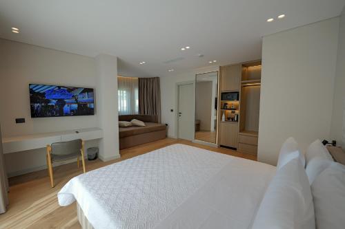 a bedroom with a white bed and a couch at Hotel Teuta in Sarandë