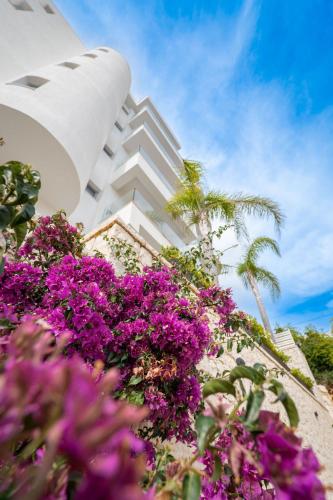 a white building with purple flowers in front of it at Hotel Teuta in Sarandë