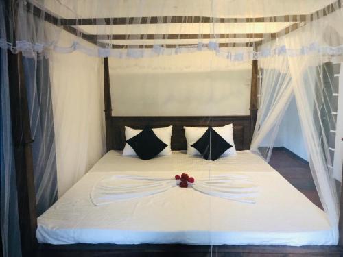 a bedroom with a white bed with a red flower on it at Bimsara Mount Villa in Weligama
