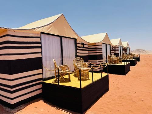una fila de tiendas con sillas en el desierto en Desert Bedouin adventure, en Wadi Rum
