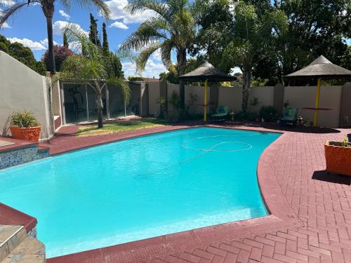 a swimming pool in a yard with trees and a fence at SiBella guest house in Bloemfontein