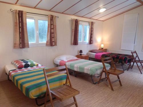 a room with three beds and a table and chairs at Couette et Tartinettes in Bretagne-dʼArmagnac