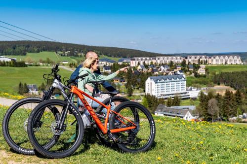 a woman sitting on a hill with her bike at Best Western Ahorn Hotel Oberwiesenthal – Adults Only in Kurort Oberwiesenthal
