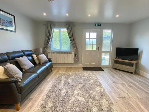 a living room with a leather couch and a television at Bow Cottage in Bridport