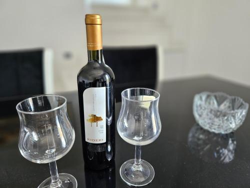 a bottle of wine and two wine glasses on a table at GREY LUXURY HOUSE in Ýpsos