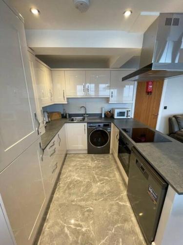 a kitchen with white cabinets and a dishwasher in it at Penthouse Flat in Scarborough in Scarborough