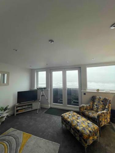 a living room with a chair and a tv and windows at Penthouse Flat in Scarborough in Scarborough