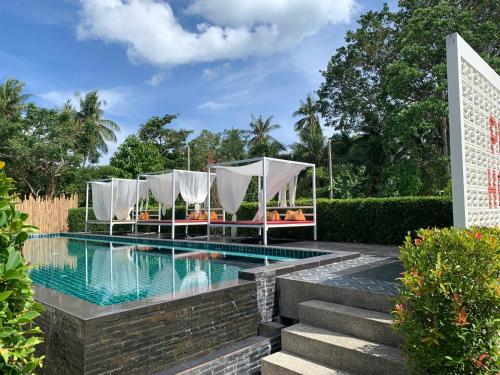a pool with chairs and a gazebo next to a resort at Phangan Hometown Resort - Adults Only in Baan Tai