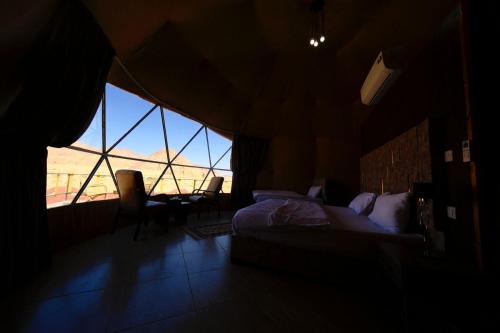 una camera con un letto e una grande finestra di Adel rum camp bubbles a Wadi Rum