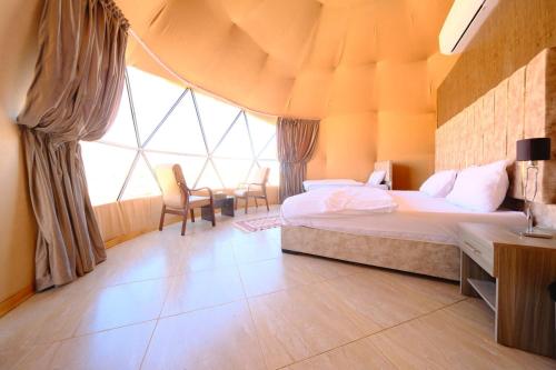 um quarto com uma cama e uma grande janela em Adel rum camp bubbles em Wadi Rum