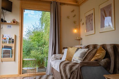 - un salon avec un canapé et une grande fenêtre dans l'établissement Tiny house au cœur du marais, à Saint-Omer