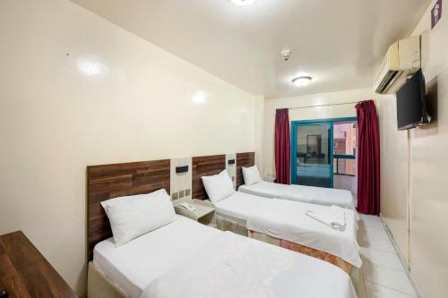 una camera d'albergo con due letti e una televisione di Naif Palace Hotel a Dubai