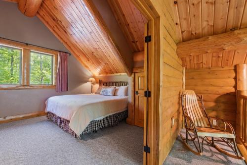 a bedroom in a log cabin with a bed and a chair at 803 Mountain Cabin in Boyne Falls