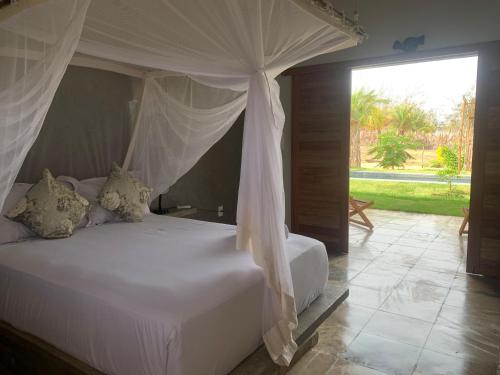 a bedroom with a white bed with a canopy at Vila Kavaju Preá in Prea