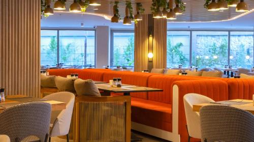 a restaurant with orange seats and tables and windows at Kleopatra Dreams Beach Hotel in Alanya