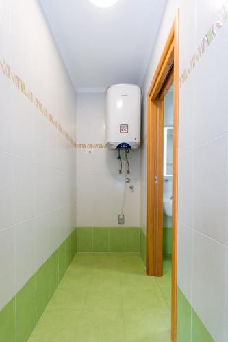 a small bathroom with a water tank and green tiles at Domus Lauri Palace Resort in Umag