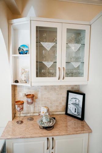 a kitchen with white cabinets and a counter with wine glasses at Vila Matias 8 in Gjirokastër
