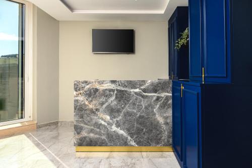a kitchen with blue cabinets and a tv on a wall at XVI Suites - Adults Only in Naxxar