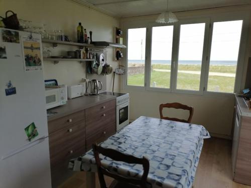 une cuisine avec une table et un réfrigérateur dans l'établissement Maison sur la dune, à Lestre