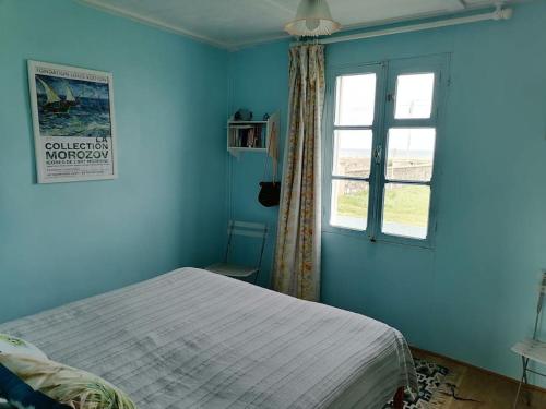 une chambre bleue avec un lit et une fenêtre dans l'établissement Maison sur la dune, à Lestre