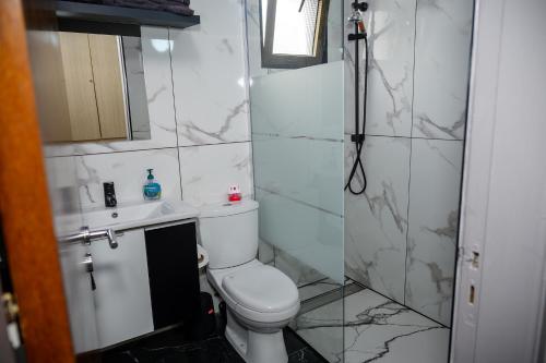 y baño blanco con aseo y ducha. en Demetris apartment en Meneou