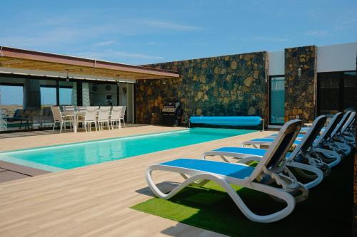 - un groupe de chaises longues à côté de la piscine dans l'établissement Villa Relajares, à Lajares