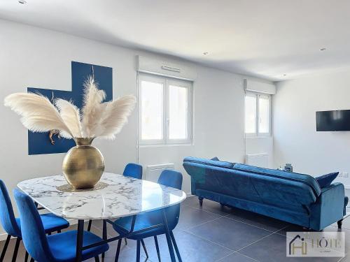 a dining room with a table and a blue couch at Marine Serenity - Appartement à 50m de la plage in Bray-Dunes