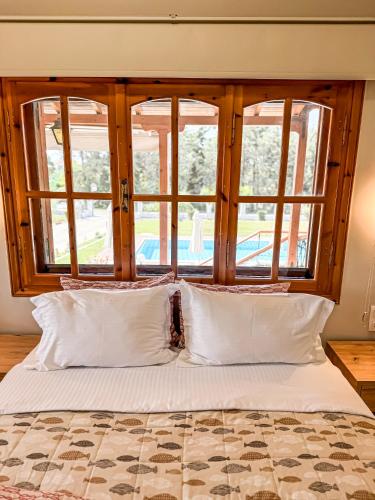 a bed with white pillows in front of a window at Kalisun Pool House by Georgalas in Nea Kalikratia