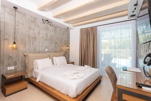 a bedroom with a large white bed and a desk at Royal Hotel and Suites in Polychrono