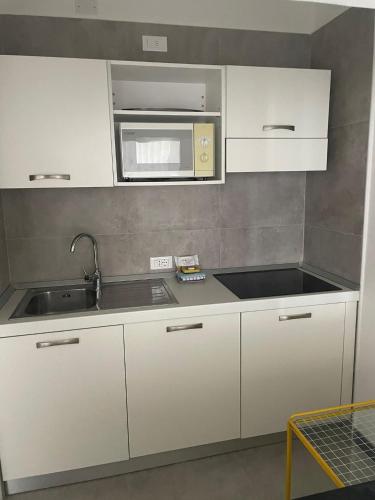 a kitchen with white cabinets and a sink and a microwave at Portofino Est Residence in Rapallo