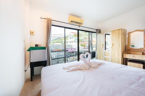 a bedroom with a white bed with a heart decoration on it at Fora Boutique Hotel in Karon Beach