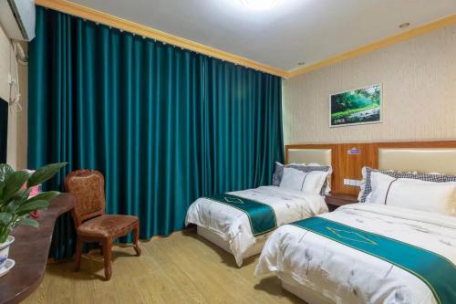Cette chambre comprend deux lits et un bureau. dans l'établissement Zhangjiajie Tianmen Mountain Aribadi Inn, à Zhangjiajie