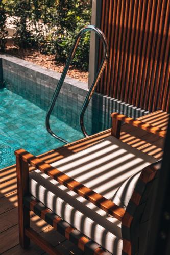 a wooden bench sitting next to a swimming pool at M Boutique Hotel - Designed for Adults in Paphos City