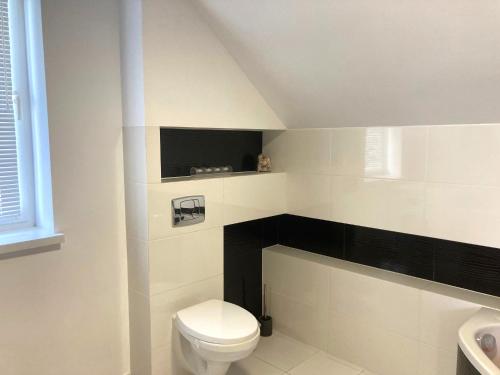 a white bathroom with a toilet and a sink at Tymi3 Dom na wzgórzu przy stoku in Przemyśl