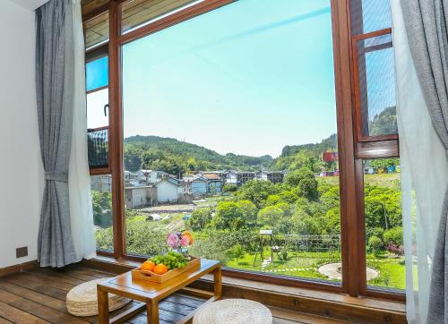 a room with a large window and a table with fruit on it at Pure House in Zhangjiajie