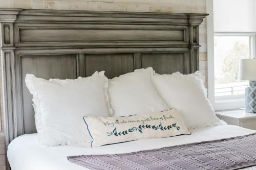 a bed with white pillows and a gray headboard at Kaya Cottages in Dahlonega