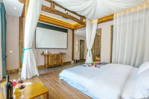 a bedroom with a white bed and a projection screen at Pure House in Zhangjiajie