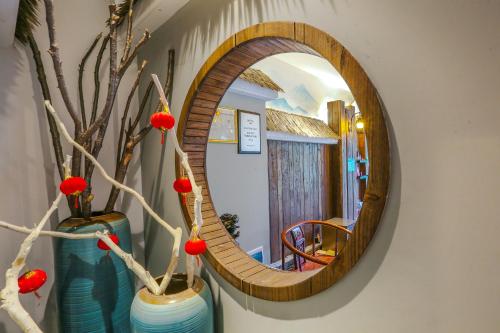 a round mirror in a hallway with vases and flowers at Pure House in Zhangjiajie