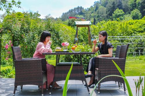 two women sitting at a table in a garden at Pure House in Zhangjiajie
