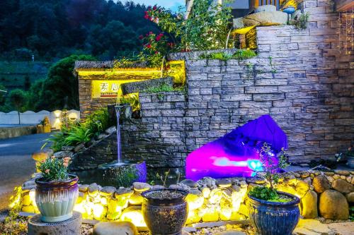 a stone wall with a fire pit with potted plants at Pure House in Zhangjiajie